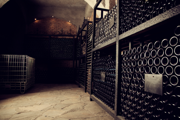 a dark wine cellar with hundreds of black bottles lining the shelves