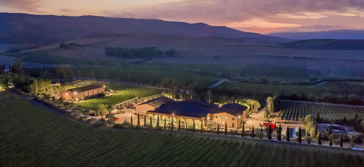 The Donnafugata winery at dusk, taken from above. Vineyards and mountains surrounding the building