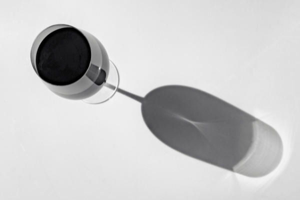 overhead view of a glass of red wine casting a long shadow