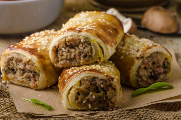 four sausage rolls stacked on a country counter