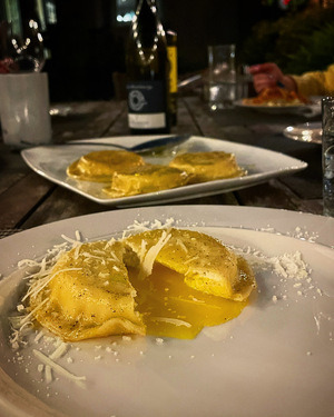 ravioli al'uovo cut open and oozing yolk on a dinner plate