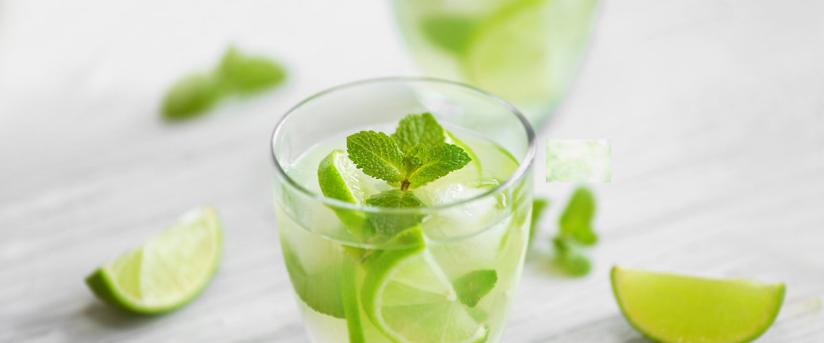 two glasses of lime and herb drink on a white background