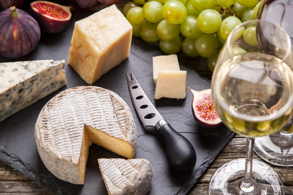 side view of a cheeseboard with a glass of red and glass of white wine beside it