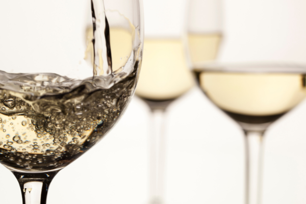 three glasses of white wine against a white background