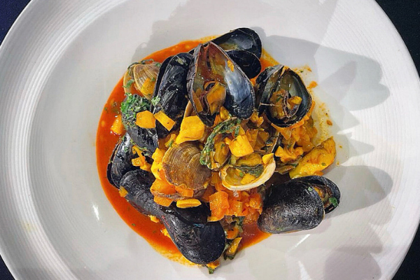 overhead view of a red seafood bisque in a white bowl
