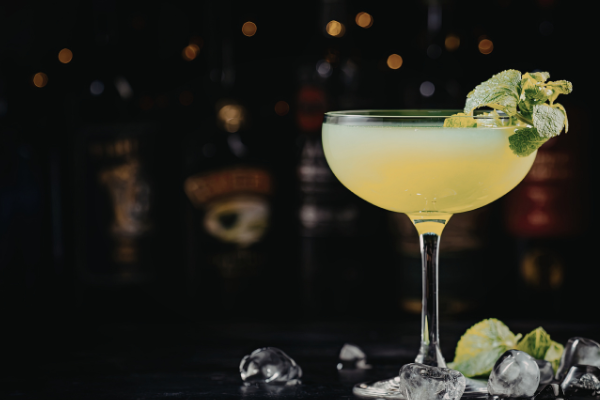 A pale green cocktail in a coup garnished with mint