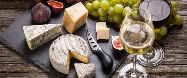a cheese board with a glass of red and a glass of white beside it
